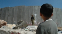 Un enfant palestinien et un soldat israélien devant la barrière de séparation israélienne