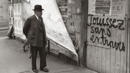 Un passant âgé Rue de Vaugirard devant un slogan de mai 68